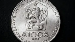Stará československá mince 100 Kčs se znakem socialistické republiky na černém pozadí.