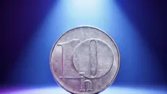 Česká desetihaléřová mince osvětlená modrým světlem na tmavém pozadí