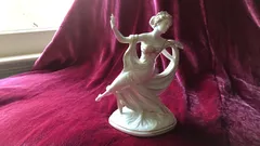 Porcelánová soška tanečnice na červeném sametu, elegantní dekorace.